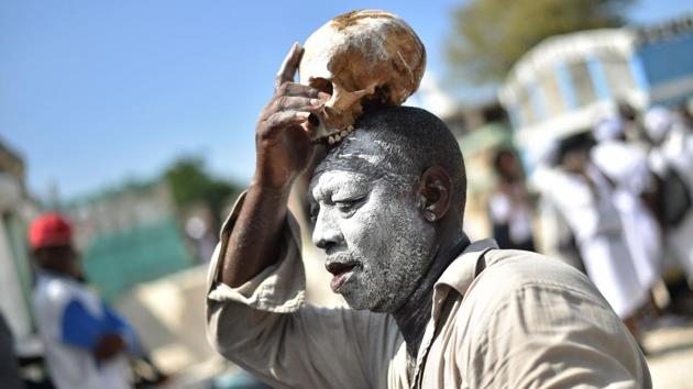A voodoo devotee with a skull on top of his head is seen during Day of the Dead in the Cementery of Cite Soleil, in Port-au-Prince. Fete Gede is in many ways the Haitian alternative to the Mexican Day of the Dead, Mardi Gras and Halloween. (Hector Retamal / AFP) A voodoo devotee with a skull on top of his head is seen during Day of the Dead in the Cementery of Cite Soleil, in Port-au-Prince. Fete Gede is in many ways the Haitian alternative to the Mexican Day of the Dead, Mardi Gras and Halloween. (Hector Retamal / AFP)