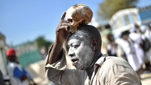 A voodoo devotee with a skull on top of his head is seen during Day of the Dead in the Cementery of Cite Soleil, in Port-au-Prince. Haitians loaded with rum, cigarettes and caked in ghostly layers of talcum took to cemeteries in the two-day Fete Gede celebration honouring dead ancestors and the master of all voodoo spirits, Baron Samdi. (Hector Retamal / AFP) A voodoo devotee with a skull on top of his head is seen during Day of the Dead in the Cementery of Cite Soleil, in Port-au-Prince. Haitians loaded with rum, cigarettes and caked in ghostly layers of talcum took to cemeteries in the two-day Fete Gede celebration honouring dead ancestors and the master of all voodoo spirits, Baron Samdi. (Hector Retamal / AFP)
