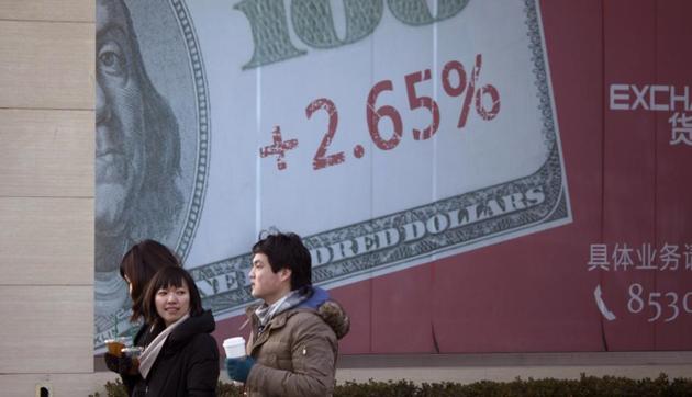 Chinese pedestrians walk past a giant US dollar note on a display board of a bank in Beijing. (AP File Photo) Chinese pedestrians walk past a giant US dollar note on a display board of a bank in Beijing. (AP File Photo)
