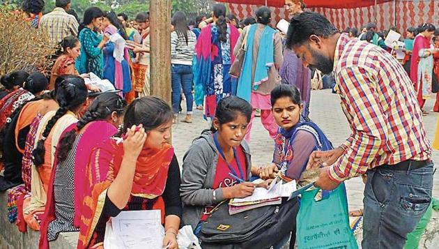 Aspirants filling forms at job fair organised at district industry centre on Friday. Monthly minimum wage for unskilled workers is Rs 7,568.5, daily wage is Rs 291.5 and hourly wage is Rs 36.4.(Gurminder Singh/HT)