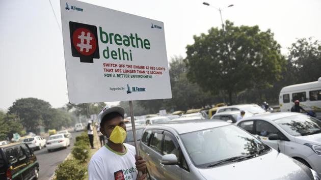 A boy wears a mask and holds a placard to address the alarming air pollution levels in the national capital.(Burhaan Kinu/HT file)