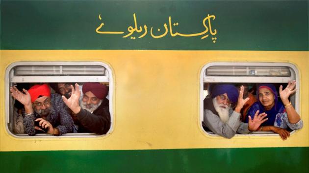 Members of a Sikh Jatha wave from train windows while departing for Pakistan to celebrate the 548th birth anniversary of Guru Nanak Dev, in Amritsar on Thursday. (PTI)
