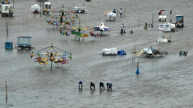 People walk through a flooded area of Marina Beach on the Bay of Bengal coast after heavy rains lashed Chennai for the eighth day.(AFP)