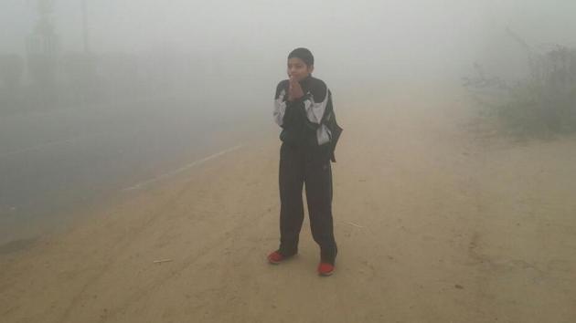 A student waiting for his schoolbus amid dense smog in Rohtak on Tuesday. (Manoj Dhaka/HT) A student waiting for his schoolbus amid dense smog in Rohtak on Tuesday. (Manoj Dhaka/HT)