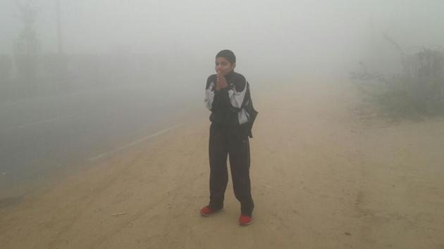 A student waiting for his schoolbus amid dense smog in Rohtak on Tuesday. (Manoj dhaka/HT)