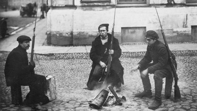 Armed revolution workers Ivanov, Yarosh and Gribovsky (L-R) warm themselves at a bonfire in St.Petersburg, Russia in October 1917. On October 25 1917 (November 07, Gregorian calendar) the Red Guard under the authority of the Bolshevik Central Committee launched an armed uprising in Petrograd to seize government facilities, communication and vantage locations, to little opposition. (Russian State Archive of Social and Political History via AP)
