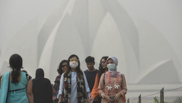 Foreign tourists wear masks as they visit the Lotus Temple on a smoggy morning in New Delhi on Tuesday.(Burhaan Kinu/HT Photo)