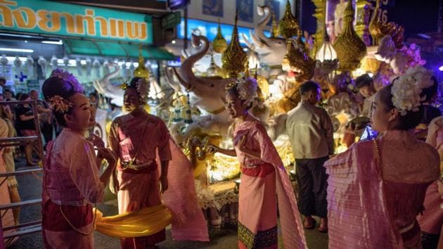 Women dressed in traditional Thai attire enjoy a light moment as they pose for photos in front of a float before the beginning of a parade in Chiang Mai. (Roberto Schmidt / AFP)