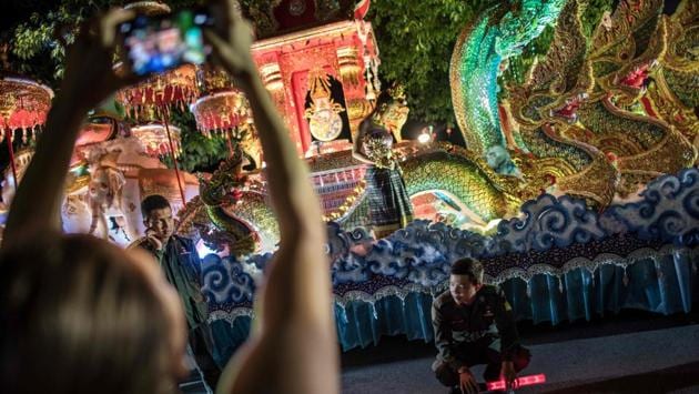Policemen guard a parade float as a spectator uses her mobile to take a photograph of the scene in a street of downtown Chiang Mai. Thousands of people that include tourists and locals alike line the streets to watch the display of elaborate floats. (Roberto Schmidt / AFP)