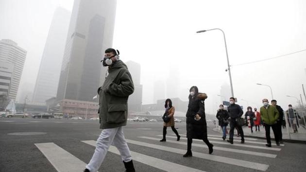 File photo of a man wearing a respiratory protection mask walks toward an office building during the smog after a red alert was issued for heavy air pollution in the Chinese capital, Beijing.(Reuters File Photo)