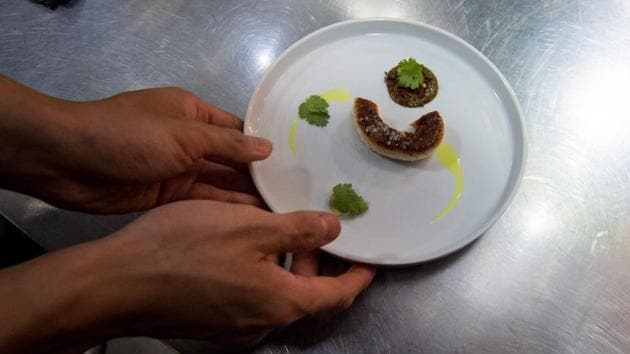 A staff member plates a dish of lobster, one of 22 served to each diner, in the kitchen at Ultraviolet restaurant. This course was paired with footage of ocean waves crashing on the walls and the scent of sea air blowing into the room. (Chandan Khanna / AFP) 
