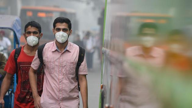 Commuters wear masks as they walk along a road amid heavy smog in New Delhi on Thursday.(AFP photo)