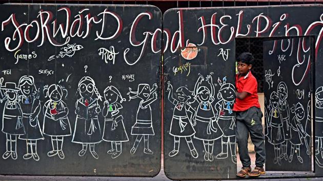 A boy looks on while standing on a school gate at Bandra, Mumbai. (Satyabrata Tripathy / HT Photo)