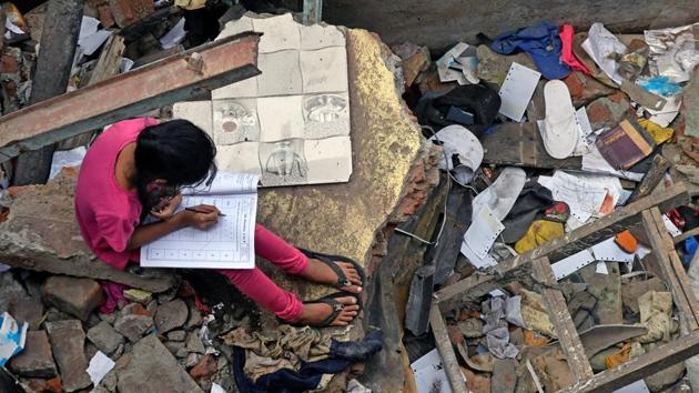 A girl studies between demolished shanties at Garib Nagar in Mumbai on Tuesday. (Shashi S Kashyap / HT Photo)