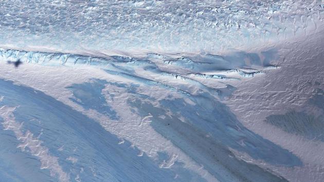 The shadow of NASA’s Operation IceBridge research aircraft (L) is seen cast over blue ice, in the Antarctic Peninsula region, on October 31, 2017. The aircraft houses sophisticated instruments for measuring snow depth, ice elevation and thickness, surface temperature, bed topography and other characteristics of sea ice, ice sheets and glaciers. (Mario Tama / Getty Images / AFP)