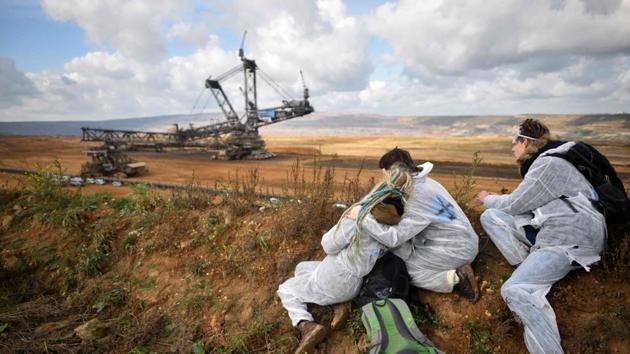 Activists look on as policemen prevent other environmentalists from marching further after they managed to enter the Hambach lignite open pit mine near Elsdorf, Germany on November 5, 2017, during a protest against fossil-based energies like coal and their negative impact on climate change. (Sascha Schuermann / AFP) 