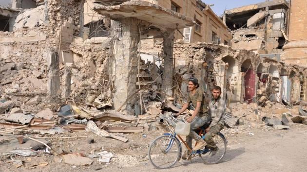 Men ride a bicycle in the eastern Syrian city of Deir Ezzor during a military operation by government forces against the Islamic State (IS) on November 4, 2017. On November 3, Russian-backed Syrian regime forces took full control of Deir Ezzor, which was the last city where IS still had a presence after being expelled from Hawija and Raqa last month. (Stringer / AFP) Men ride a bicycle in the eastern Syrian city of Deir Ezzor during a military operation by government forces against the Islamic State (IS) on November 4, 2017. On November 3, Russian-backed Syrian regime forces took full control of Deir Ezzor, which was the last city where IS still had a presence after being expelled from Hawija and Raqa last month. (Stringer / AFP)