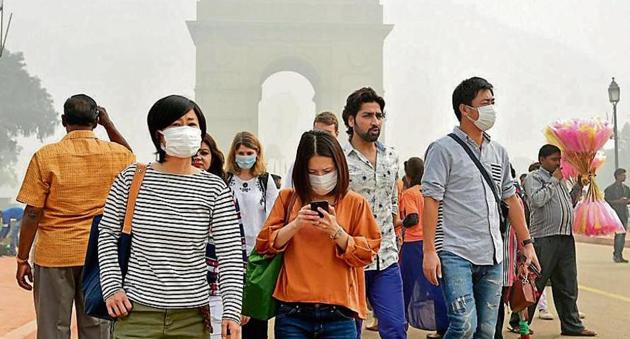 People wear protective masks at Rajpath as pollution level remained severe in the Capital on Sunday.(PTI)