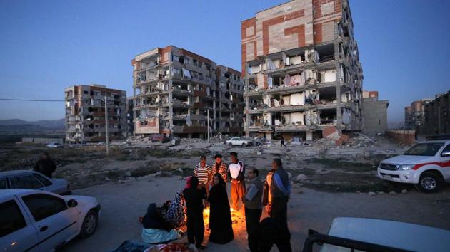 Survivors warm themselves in front of destroyed buildings after an earthquake at the city of Sarpol-e-Zahab in western Iran. A powerful earthquake shook the Iran-Iraq border, killing more than 300 people and injuring over 2,500 in the mountainous region of Iran alone, state media there said. Some 50 aftershocks have followed. Baghdad did not immediately release information about damage or casualties in Iraq. (Pouria Pakizeh / ISNA via AP) Survivors warm themselves in front of destroyed buildings after an earthquake at the city of Sarpol-e-Zahab in western Iran. A powerful earthquake shook the Iran-Iraq border, killing more than 300 people and injuring over 2,500 in the mountainous region of Iran alone, state media there said. Some 50 aftershocks have followed. Baghdad did not immediately release information about damage or casualties in Iraq. (Pouria Pakizeh / ISNA via AP)