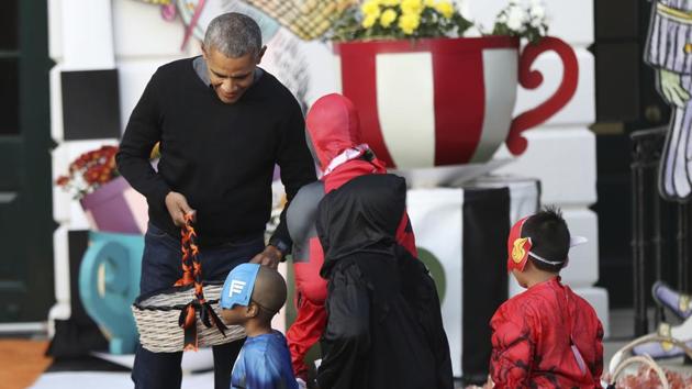 Barack Obama hands treats as he and first lady Michelle Obama welcome children from Washington area and children of military families to trick-or-treat celebrating on Halloween, October 31, 2016. (AP File Photo)