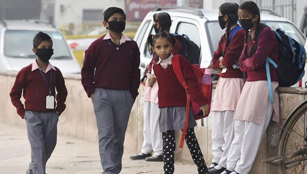 Children, wearing masks as protection against smog and air pollution, wait for their school bus in New Delhi. (PTI) Children, wearing masks as protection against smog and air pollution, wait for their school bus in New Delhi. (PTI)
