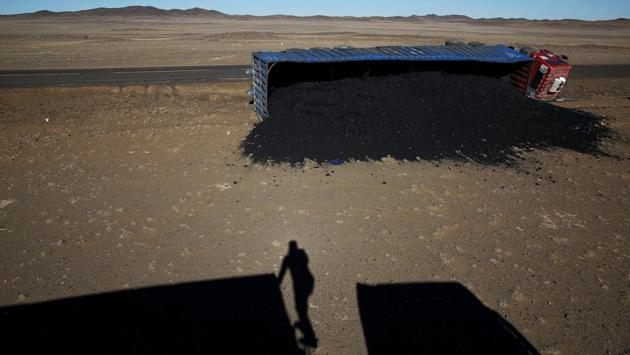 A photographer casts his shadow near a coal truck which flipped over at Khanbogd Soum, in the Gobi desert, Mongolia. Getting to the border can be a harrowing ordeal, as vehicles speed towards China and back down the one-lane road. With no street lamps to guide the way and drunk-driving a constant problem, danger levels increase at night. (B. Rentsendorj / Reuters)