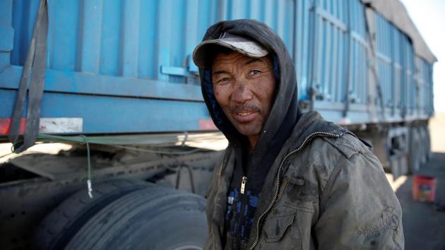 A truck driver repairs his truck on the side of the road near the China-Mongolia border. With Gobi miners hoping to boost output further next year in a bid to take advantage of higher prices in China the bottlenecks are expected to get worse. (B. Rentsendorj / Reuters)