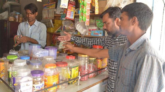 Customers buy goods at a shop in Ajmer. Goods such as shampoo and detergents should have cost less from November 15, but it didn’t happen because companies can’t immediately change the prices displayed on products already in stores. (HT file photo)