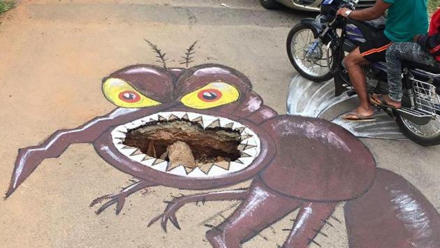 One local artist Baadal Nanjundaswamy has found a creative use for the potholes, painting elaborate murals around the craters to both beautify the city and alert motorists to danger. (Courtesy: Baadal Nanjundaswamy’s Facebook page)