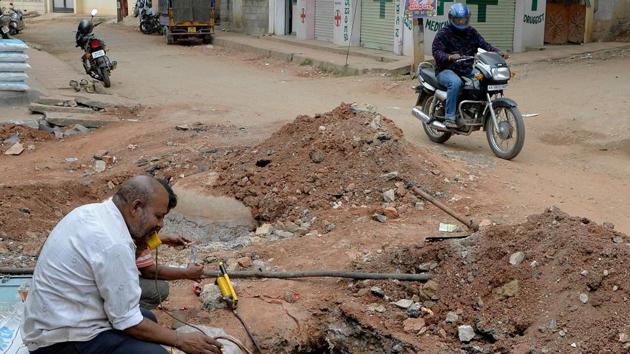 Workers of a telecom company working around a trench dug up along a road in Bangalore. A slew of road deaths blamed on potholes sparked angry protests across the city. (Manjunath Kiran / AFP)