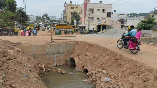 This photograph taken on November 1, 2017 shows a motorist passing an open sewage canal under repair in Bangalore. (Manjunath Kiran / AFP)