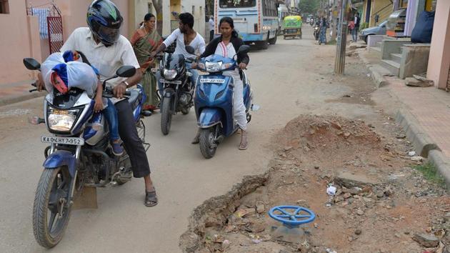 In this photograph taken on November 1, 2017, motorists ride past a pothole created during road repair work in Bangalore. (Manjunath Kiran / AFP)