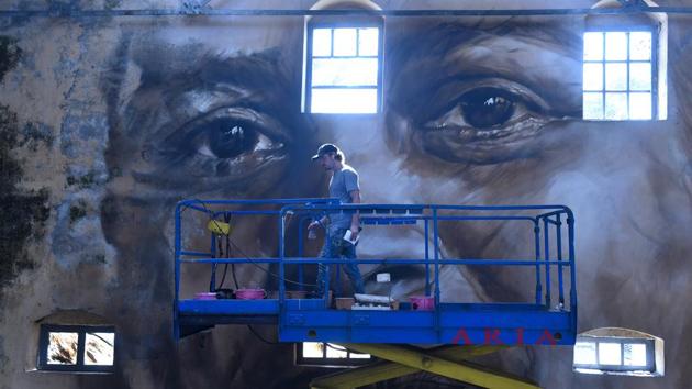 Australian artist Guido Van Helten paints a portrait of a lady as part of the Sassoon Dock Art Project at Sassoon Dock.Thirty artists from around the world have given the bustling 142-year-old Sassoon Docks, home to Mumbai’s traditional Koli fishing community, a colourful makeover as part of the St+art Urban Art Festival. (Anshuman Poyrekar / HT Photo)