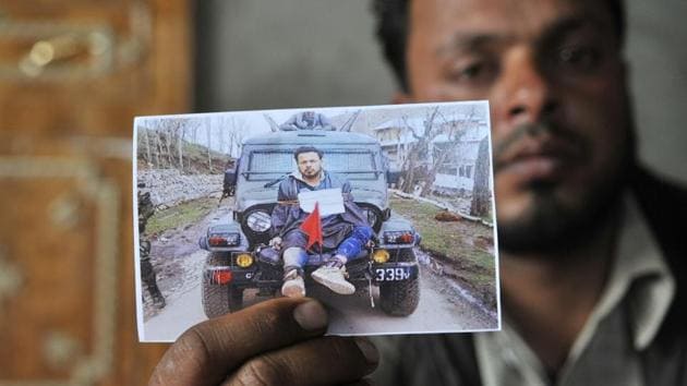 Farooq Dar, who was used as a human shield by army, sits in his home in Chill village in Budgam district and holds a picture of him being tied on a jeep.(Waseem Andrabi /HT File Photo)