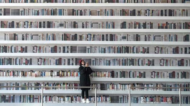 A woman takes a selfie at the Tianjin Binhai Library. This futuristic Chinese library has wowed book lovers around the world with its white, undulating shelves rising from floor to ceiling, but read between the lines and you’ll find something is missing. Those rows upon rows of book spines are mostly images printed on aluminium plates that make up the backs of shelves. (Fred Dufour / AFP) A woman takes a selfie at the Tianjin Binhai Library. This futuristic Chinese library has wowed book lovers around the world with its white, undulating shelves rising from floor to ceiling, but read between the lines and you’ll find something is missing. Those rows upon rows of book spines are mostly images printed on aluminium plates that make up the backs of shelves. (Fred Dufour / AFP)