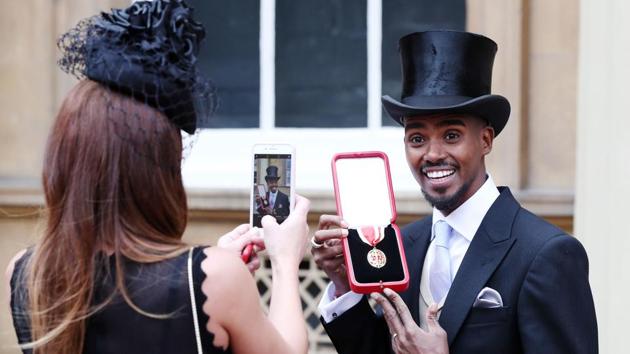 Britain's Mo Farah holds his medal and poses for a photograph for his wife Tania, after being knighted as a Knights Bachelor during an investiture ceremony at Buckingham Palace, in London on November 14, 2017. (Jonathan Brady / PA / AFP) 