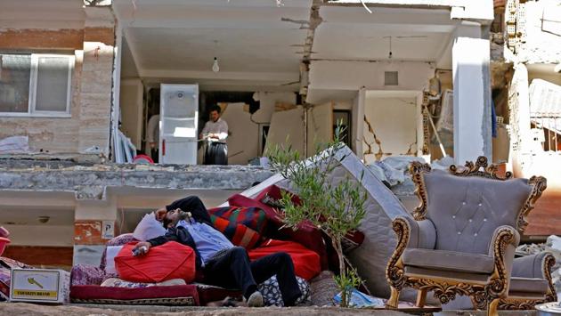 An Iranian man rests as he lies atop salvaged mattresses and items outside damaged buildings in the town of Sarpol-e Zahab in Kermanshah province near the border with Iraq on November 14, 2017, following a 7.3-magnitude earthquake that left hundreds killed and thousands homeless two days before. (Atta Kenare / AFP) 