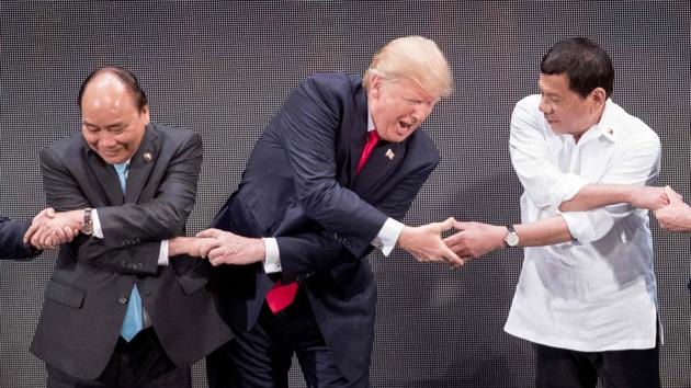 Vietnam's Prime Minister Nguyen Xuan Phuc (L), US President Donald Trump (C) and Philippine President Rodrigo Duterte join hands for the family photo during the 31st ASEAN Summit in Manila on November 13, 2017. (Jim Watson / AFP) 