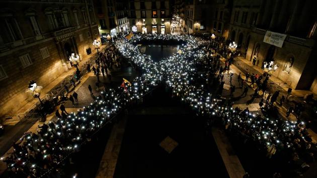 People hold their mobile phones while standing to create the shape of a giant ribbon in front of the 'Generalitat' palace, the Catalan government headquarters at the Sant Jaume square in Barcelona on November 16, 2017 during a demonstration calling for the release of jailed Catalan separatist leaders Jordi Sanchez and Jordi Cuixart. (Pau Barena / AFP) 