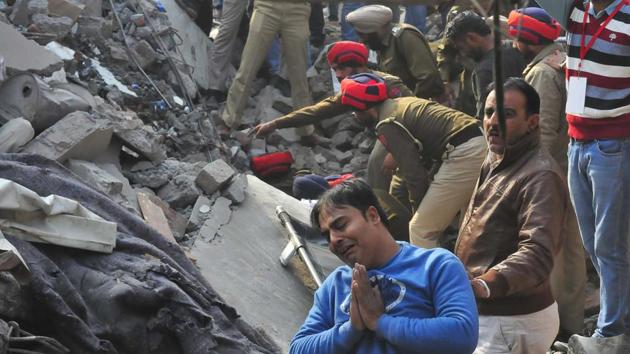 Rescue operation being carried out by the joint rescue team, while a distressed man stands nearby (Gurpreet Singh/HT)