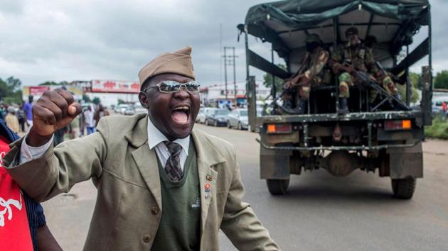 A man cheers as a military vehicle loaded with soldiers drives past him during a rally to demand the resignation of Robert Mugabe at the a public ground on November 18, 2017, in Harare. Since last week, Mugabe has been confined to his lavish “Blue Roof” residence in Harare, apart from two trips to State House to meet generals and one to a university graduation ceremony. (AFP Photo) A man cheers as a military vehicle loaded with soldiers drives past him during a rally to demand the resignation of Robert Mugabe at the a public ground on November 18, 2017, in Harare. Since last week, Mugabe has been confined to his lavish “Blue Roof” residence in Harare, apart from two trips to State House to meet generals and one to a university graduation ceremony. (AFP Photo)