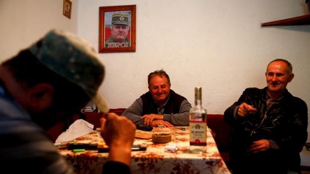 Dusko Mladic (C), first cousin of Ratko Mladic, at a tavern in Bozanovici. Mladic is accused of ordering the killing of 8,000 unarmed Muslim men and boys after the capture of Srebrenica, and raining artillery on civilians during the siege of Sarajevo. Here in his village, Mladic is, as the slogan on his portrait above the drinkers declares, “a hero”. (Dado Ruvic / REUTERS) Dusko Mladic (C), first cousin of Ratko Mladic, at a tavern in Bozanovici. Mladic is accused of ordering the killing of 8,000 unarmed Muslim men and boys after the capture of Srebrenica, and raining artillery on civilians during the siege of Sarajevo. Here in his village, Mladic is, as the slogan on his portrait above the drinkers declares, “a hero”. (Dado Ruvic / REUTERS)