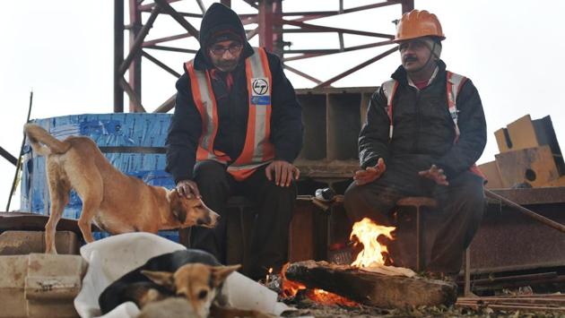Workers catch a break from the routine on a cold morning at a construction site in Mayur Vihar, New Delhi. The mercury has dipped by around four degrees over the past one week in the capital bringing respite from weeks of smog. (Sushil Kumar / HT Photo) 