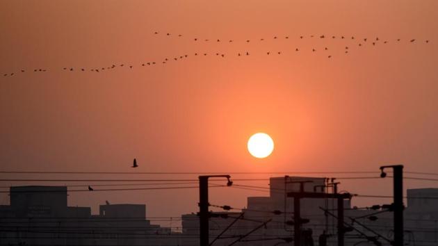 A flock of birds fly during sunrise in New Delhi on Wednesday. MeT experts of the Regional Weather Forecasting Centre said that a clear sky and strong north-westerly winds over Delhi have caused the mercury to fall and have also helped to keep pollution levels relatively low. (Sushil Kumar / HT Photo) 