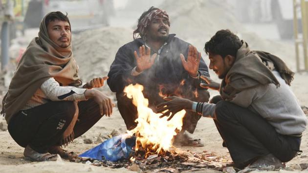 People warm themselves around a bonfire on a cold winter morning in New Delhi. To curb the practice of waste-burning during winter, Delhi environment minister Imran Hussain on Tuesday directed officials to ensure electric heaters are provided at all night shelters and to guards across government offices. (Raj K Raj / HT Photo) 