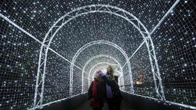 Visitors walk through a tunnel covered in lights, as part of a Christmas illuminated trail through Kew Gardens, in London on Tuesday. (Frank Augstein) / AP) Visitors walk through a tunnel covered in lights, as part of a Christmas illuminated trail through Kew Gardens, in London on Tuesday. (Frank Augstein) / AP)