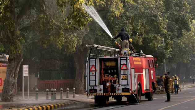 A firefighter sprays water on trees as part of the anti-pollution measures to improve air quality in Delhi on Thursday.(PTI)