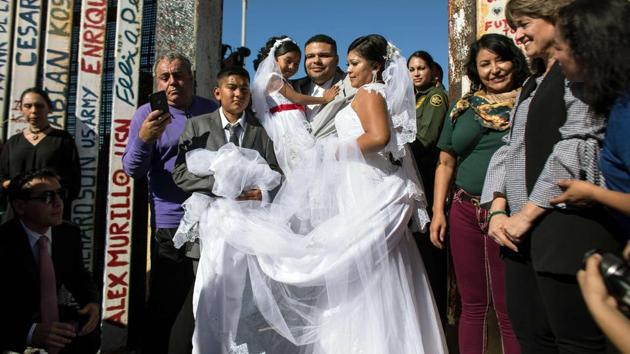 Bride Evelia Reyes and groom Brian Houston, living on different sides of the US-Mexico border, stand for a family portrait after getting married during a briefly reunited during the "Opening the Door of Hope" event at the border fence gate in Playas de Tijuana, Mexico on November 18, 2017. (Guillermo Arias / AFP) Bride Evelia Reyes and groom Brian Houston, living on different sides of the US-Mexico border, stand for a family portrait after getting married during a briefly reunited during the "Opening the Door of Hope" event at the border fence gate in Playas de Tijuana, Mexico on November 18, 2017. (Guillermo Arias / AFP)