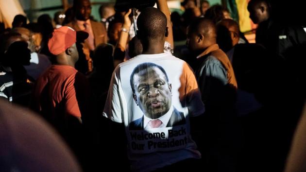 A supporter of Zimbabwe's incoming president Emmerson Mnangagwa wore a t-shirt with his portrait at Zimbabwe's ruling Zanu-PF party headquarters in Harare on November 22, 2017. Zimbabwe's former vice president Emmerson Mnangagwa flew home on November 22 to take power after the resignation of Robert Mugabe put an end to 37 years of authoritarian rule. (Marco Longari / AFP) A supporter of Zimbabwe's incoming president Emmerson Mnangagwa wore a t-shirt with his portrait at Zimbabwe's ruling Zanu-PF party headquarters in Harare on November 22, 2017. Zimbabwe's former vice president Emmerson Mnangagwa flew home on November 22 to take power after the resignation of Robert Mugabe put an end to 37 years of authoritarian rule. (Marco Longari / AFP)
