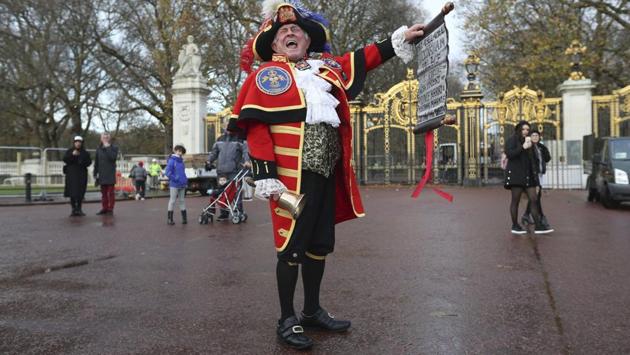 Town Crier Tony Appleton shouts as he holds a scroll outside Green Park in central London near Buckingham Palace after it was announced that Prince Harry and Meghan Markle were engaged. (Jonathan Brady / AP)